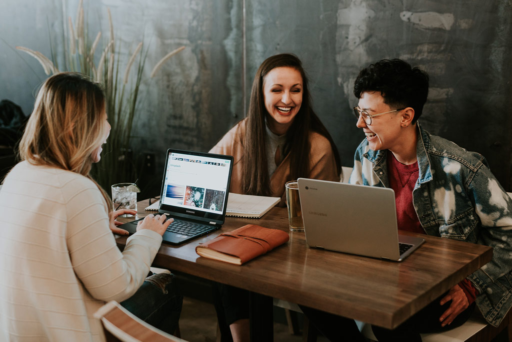 Trois femmes qui travaillent ensemble sur leurs ordinateur dans un café.