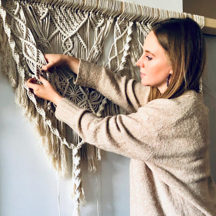 Décoratrice en train d'installer une suspension en macramé. Portrait Le Moment Events.