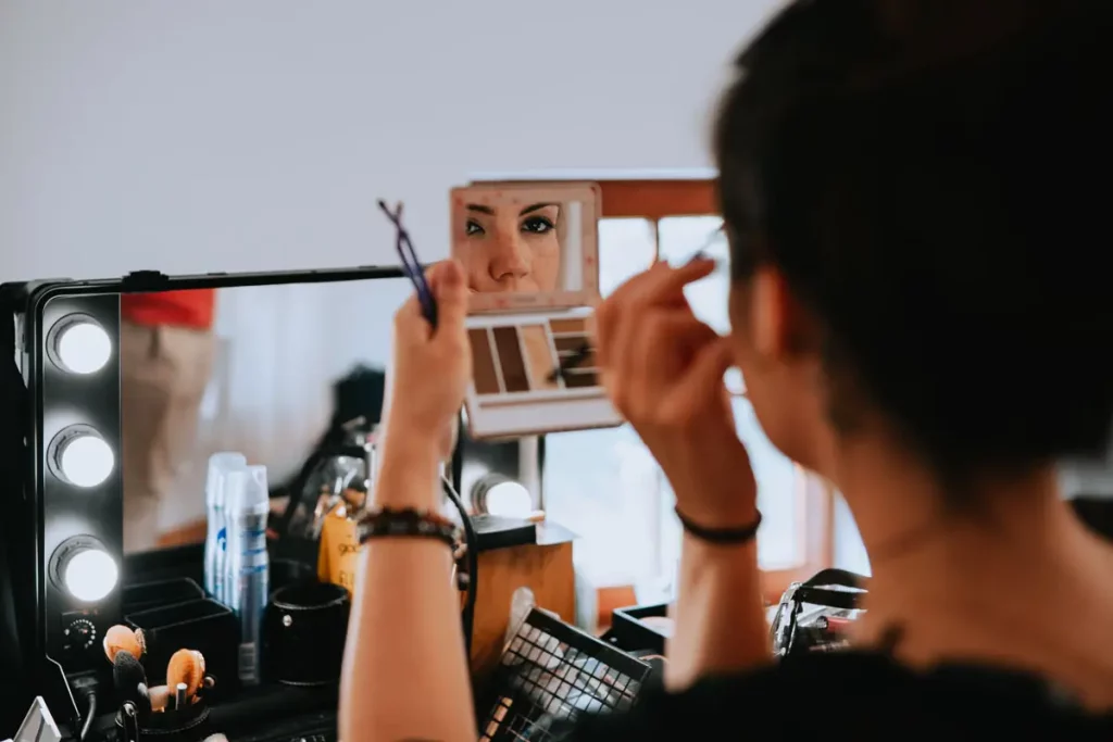 Reflet dans un miroir d'une maquilleuse professionnelle qui se maquille elle-même.